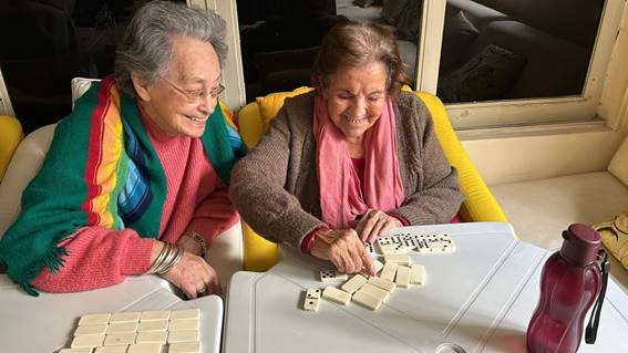 Imagem ilustrativa para deficiente: sol na varanda com várias senhoras jogando dominó na Casa de Repouso Mamma Mia, localizada no Brooklin, Zona Sul de São Paulo